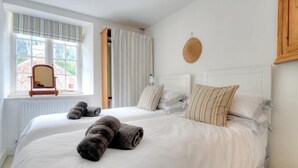 A hotel room with two beds, a window with curtains, a round wall decoration, and a wooden cabinet.