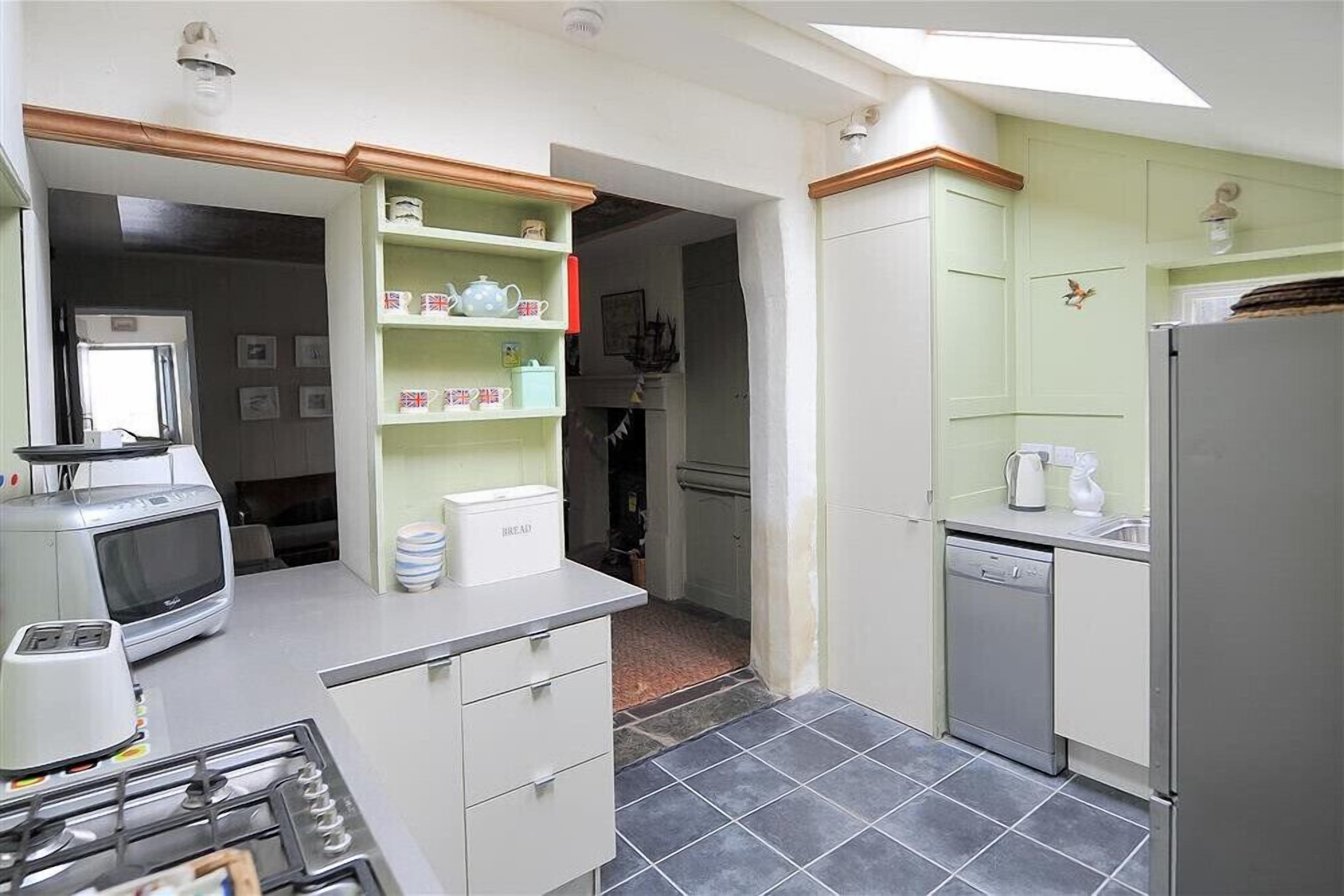 A compact kitchen with a gas stove, microwave, and a small refrigerator.