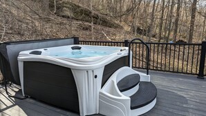 Una vasca idromassaggio su un pontile di legno, con una ringhiera metallica sullo sfondo.