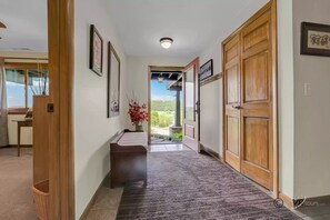 Enter a serene hallway leading to a garden view, featuring a cozy bench and framed artwork.