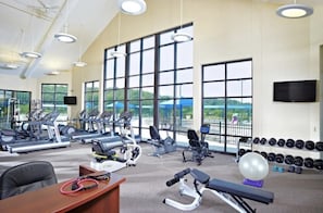 A gym with cardio machines, weightlifting equipment, and a view of the outdoors.