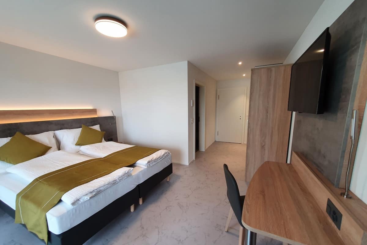 A modern hotel room with a bed, bedside table, and a TV mounted on the wall.