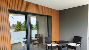 A modern balcony with glass doors, a round table, and four wicker chairs. - Hb-gästehaus (Selzach)