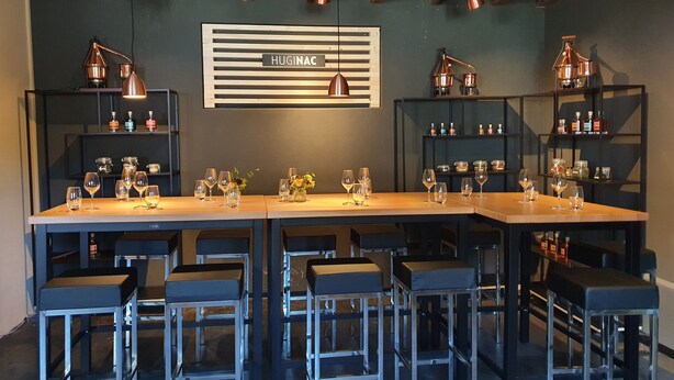A bar area with multiple stools, a long counter, and shelves with bottles and glasses. - Hb-gästehaus (Selzach)