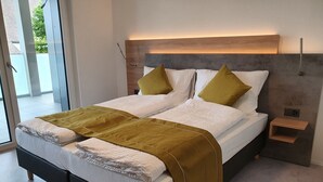 A double bed with a wooden headboard, two pillows, and a bedside table with a lamp. - Hb-gästehaus (Selzach)