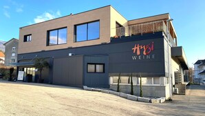 A modern building with a sign reading "tusi WEINE". - Hb-gästehaus (Selzach)