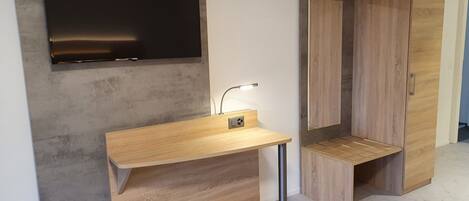 A modern bathroom with a wooden vanity, a mounted TV, and a wooden wardrobe.