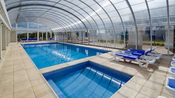 Una piscina techada, sillones reclinables de piscina