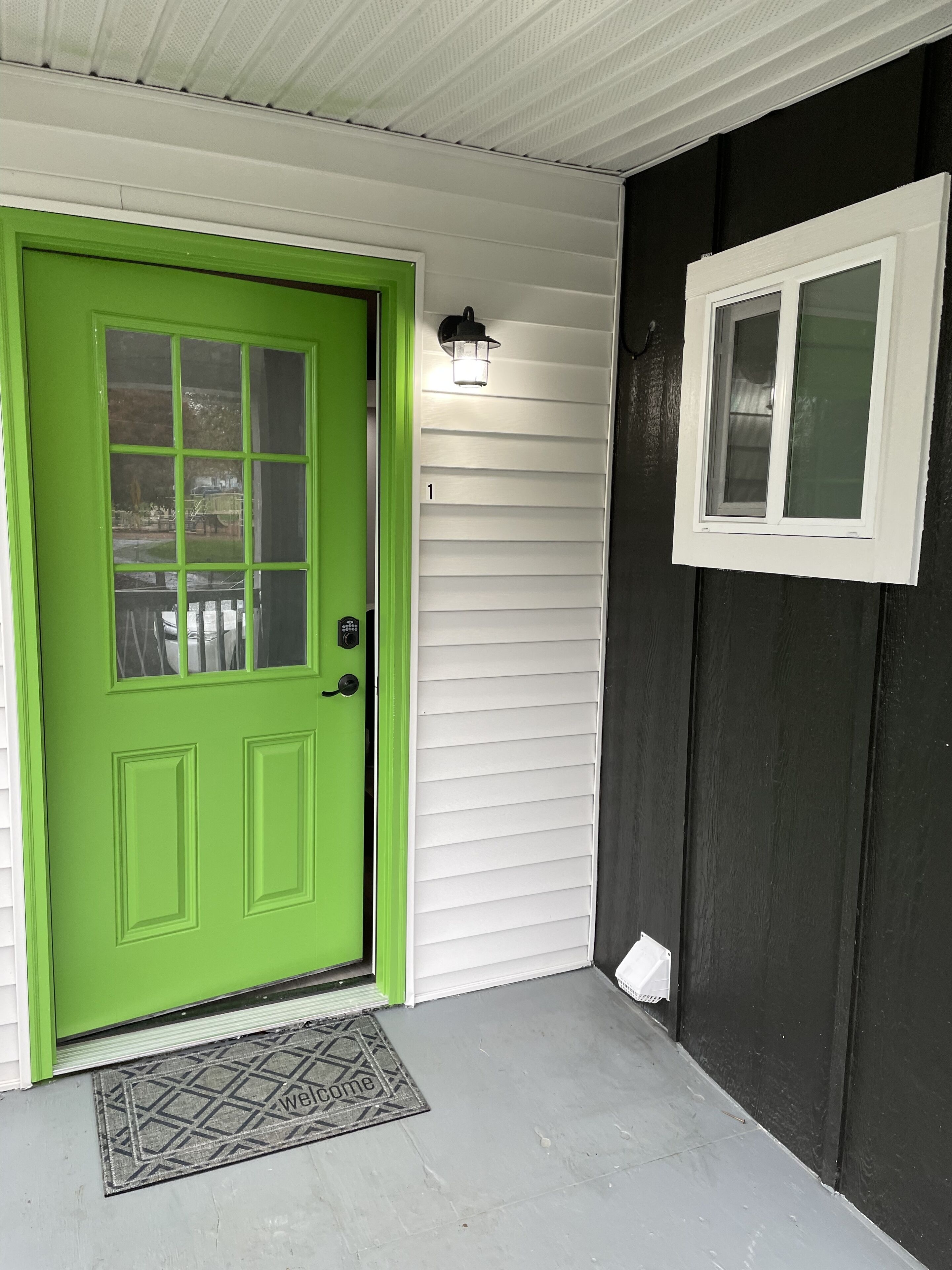 Una puerta verde con ventana, una puerta blanca con ventana y una puerta negra con ventana.