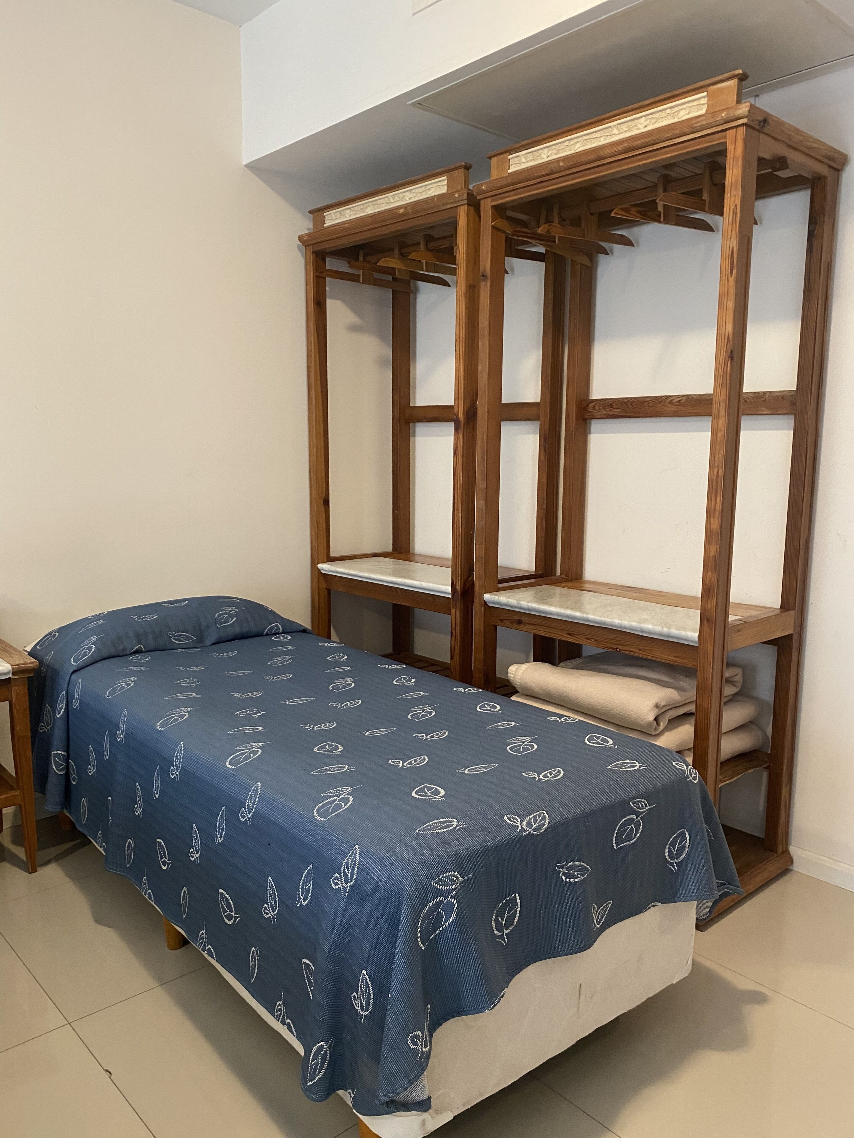 Un dormitorio con una cama individual, estantería de madera y una mesita.