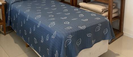 Un dormitorio con una cama individual, estantería de madera y una mesita.