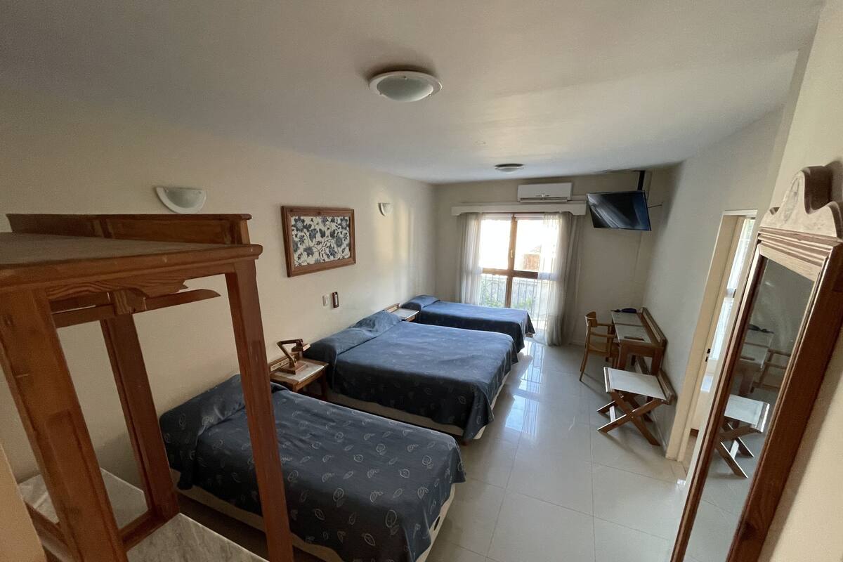 Habitación de hotel con dos camas, un escritorio, una silla, un televisor y una ventana con cortinas.