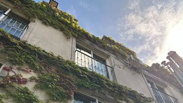 Un bâtiment doté de nombreuses fenêtres, dont certaines sont protégées par des grilles métalliques, et des unités de climatisation fixées à la façade extérieure.