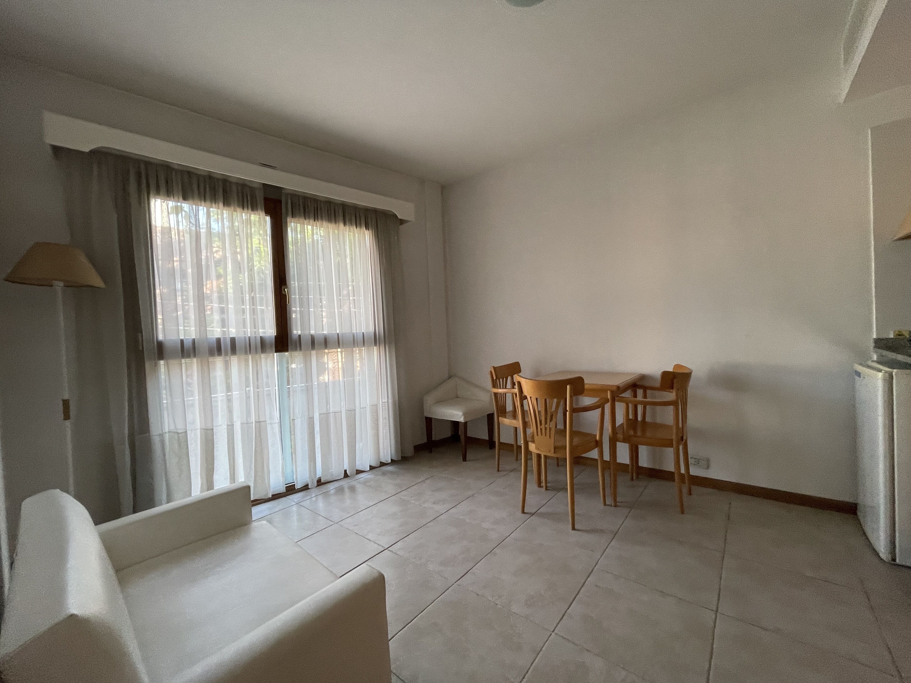 Una habitación con una mesa de comedor y sillas, un sofá y una lámpara.