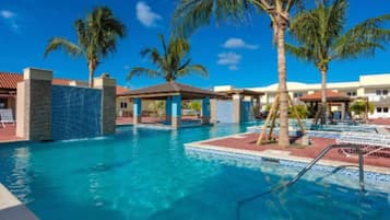 Relax by the resort pool surrounded by palm trees and lounge chairs.