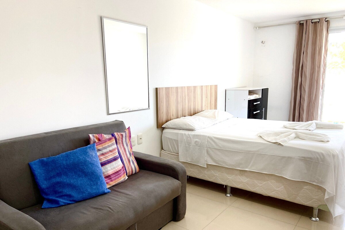 Una habitación de hotel con cama, sofá, armario y espejo.
