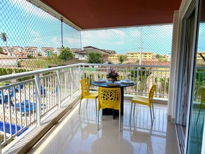 Varanda com mesa e cadeiras, vista de edifícios e uma cerca.