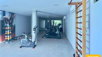 A gym with exercise equipment, a treadmill, and a wall-mounted ladder.