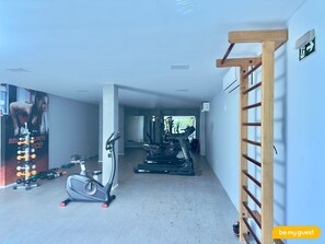 Un gimnasio con equipo de ejercicio, una cinta de correr y una escalera fijada a la pared.