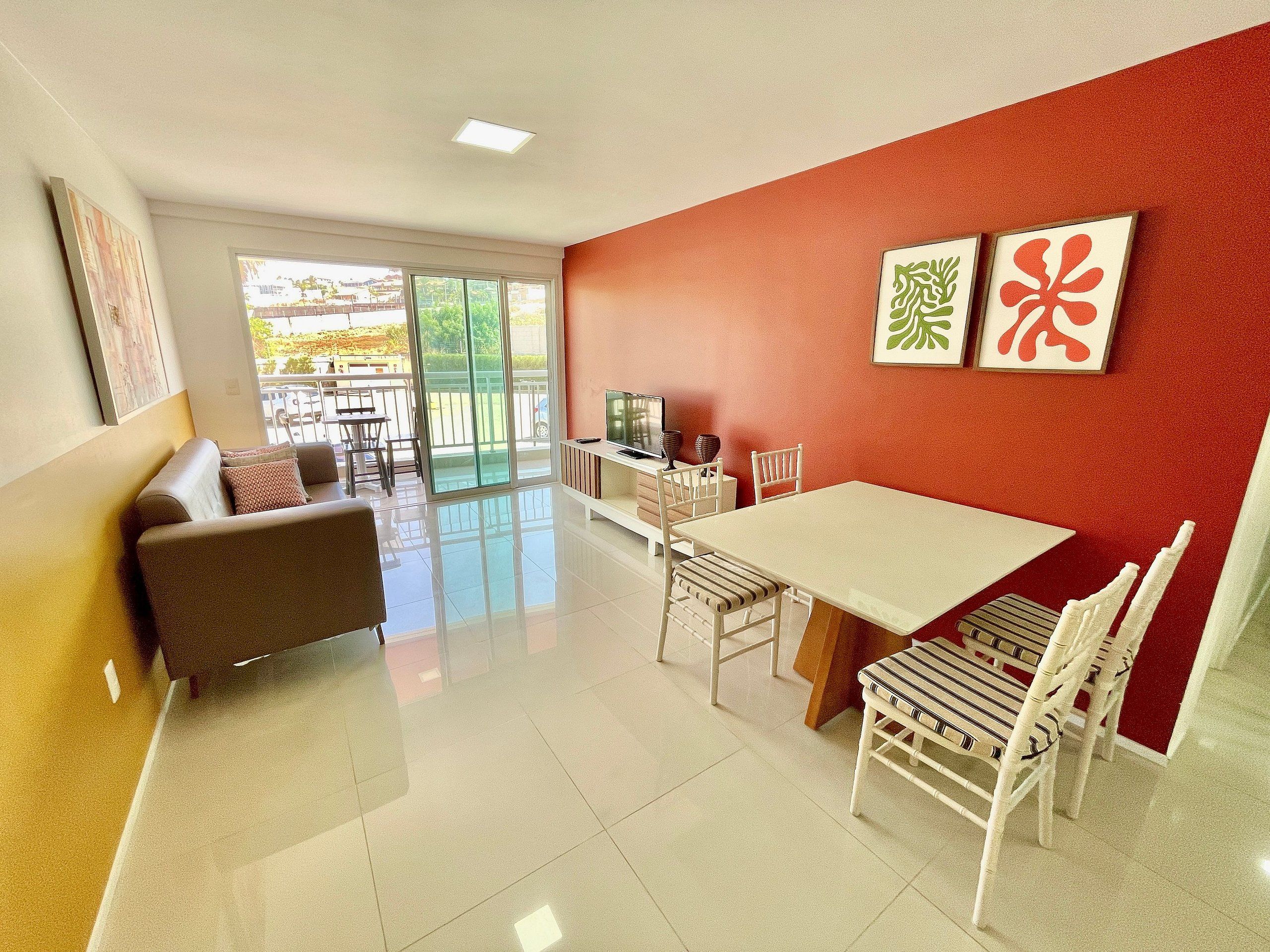 Uma sala de estar moderna com um sofá, uma mesa de jantar, cadeiras, uma televisão e obras de arte na parede.