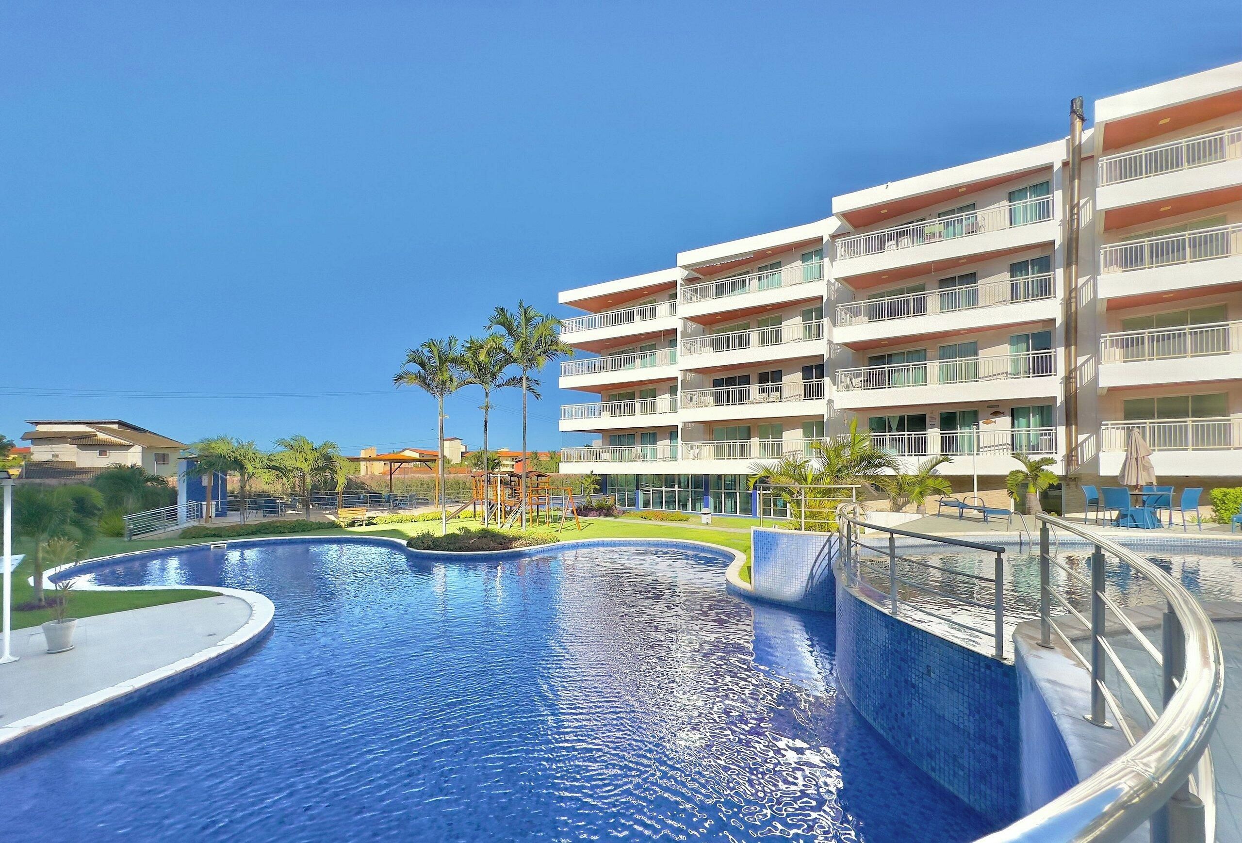 Um hotel com piscina, várias varandas e um céu azul e límpido.