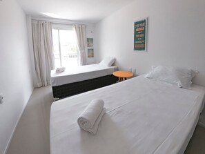 A hotel room with two beds, a small orange table, and a window with curtains. - Solarium Residence Resort (Aquiraz)