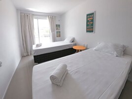 Quarto de hotel com duas camas, uma mesa pequena laranja e uma janela com cortinas.