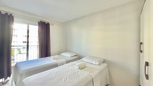 Una habitación de hotel con dos camas, una ventana con cortinas y una puerta.