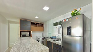 A modern kitchen with a built-in oven, a refrigerator, and a sink. - Solarium Residence Resort (Aquiraz)