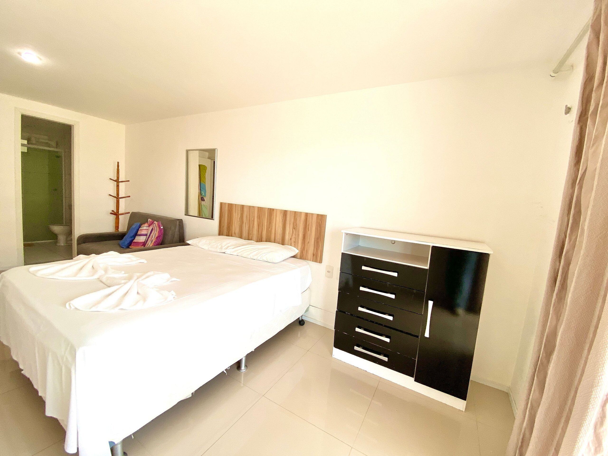 Una habitación de hotel con cama, armario, espejo y puerta que da a un baño.