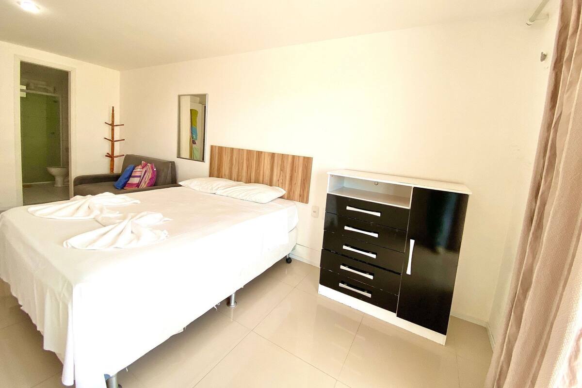 A hotel room with a bed, a wardrobe, a mirror, and a door leading to a bathroom.