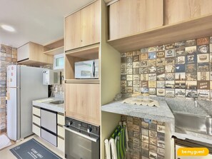 A kitchen with wooden cabinets, a built-in microwave, a stainless steel oven, and a backsplash with vintage-style tiles.