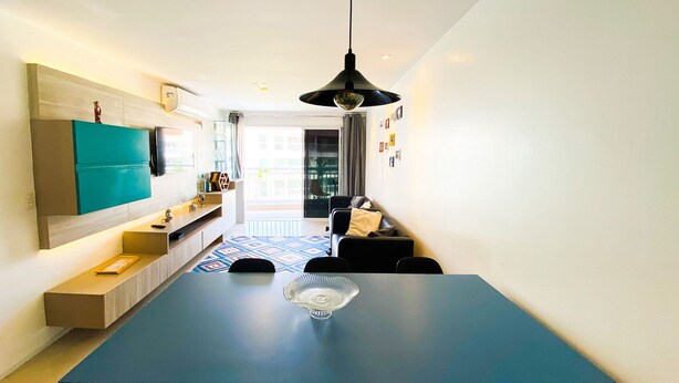 A modern kitchen with a blue dining table, a hanging pendant light, and a view to the outside. - Solarium Residence Resort (Aquiraz)