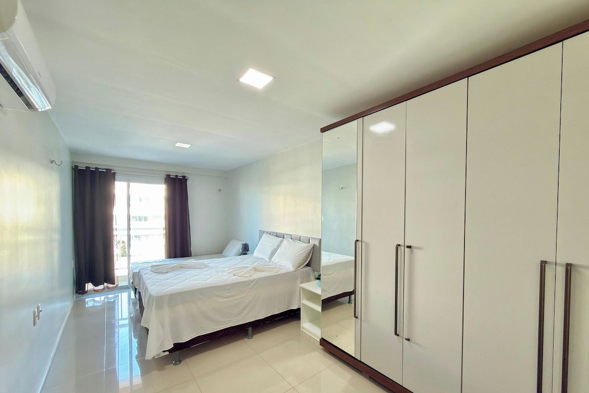 A hotel room with a bed, a wardrobe, and a window with curtains.