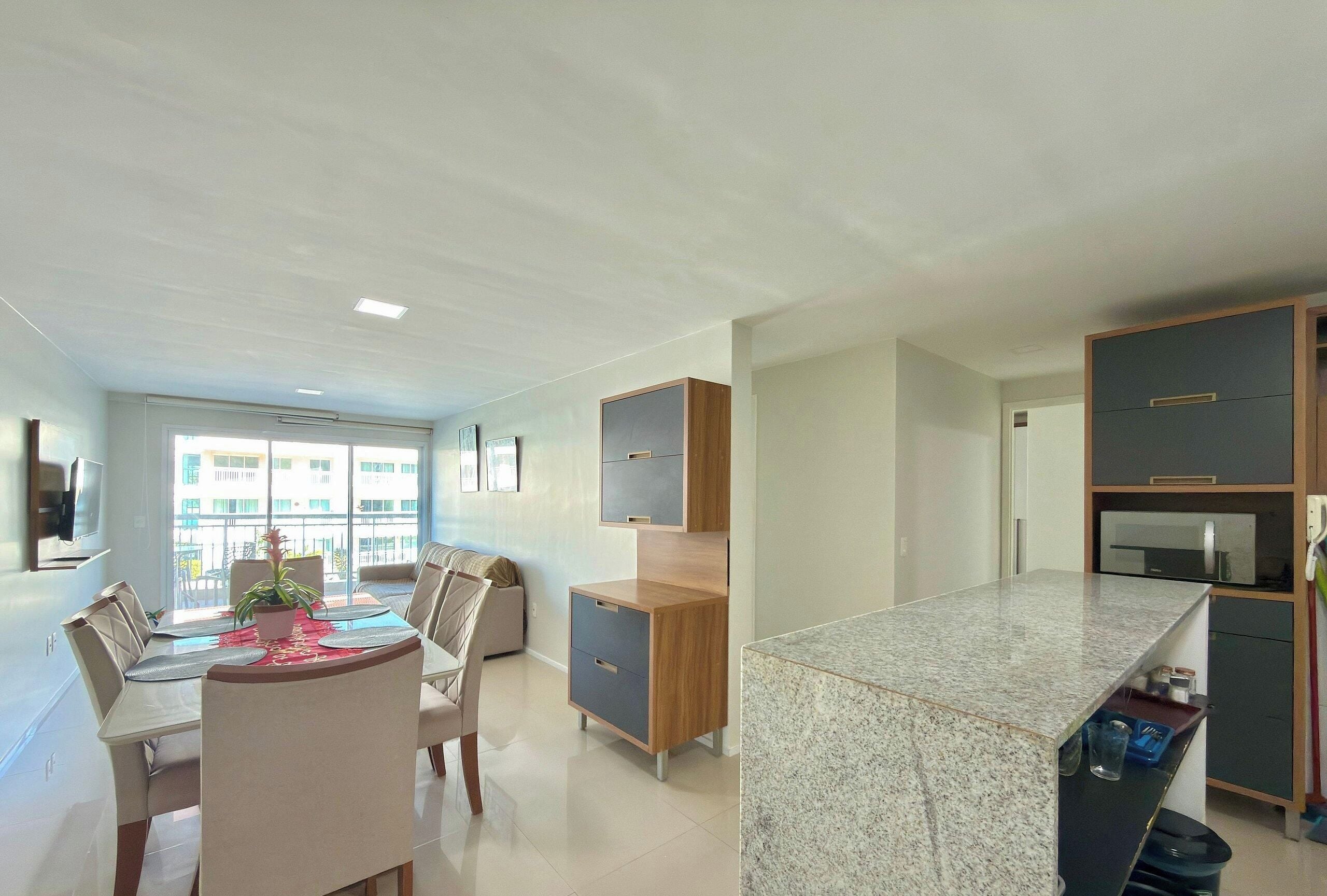 A modern kitchen with a granite countertop, wooden cabinets, and a dining area with a table and chairs.