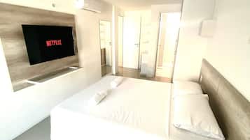 Quarto de hotel moderno com uma cama grande, televisão de tela plana na parede e design minimalista.