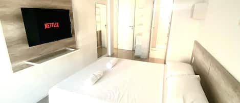 Habitación de hotel moderna con una cama grande, un televisor de pantalla plana en la pared y un diseño minimalista.