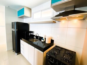 Una cocina con estufa negra, un lavabo y una cafetera.