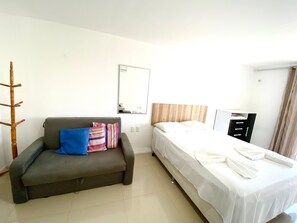 A room with a bed, a sofa, a mirror, and a wardrobe.