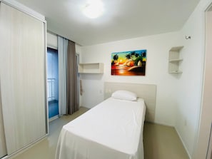 A hotel room with a bed, a painting of a sunset, a balcony door, and a ceiling light. - Solarium Residence Resort (Aquiraz)