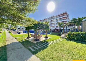 Un patio de hotel con piscina, mobiliario exterior y un parque infantil.