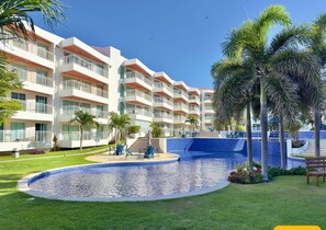 Un hotel con varios balcones, piscina y palmeras.