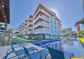 A hotel with multiple balconies, a swimming pool, and outdoor seating.