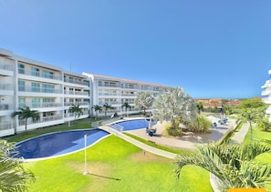 Un hotel con varios balcones, piscina y vegetación circundante.