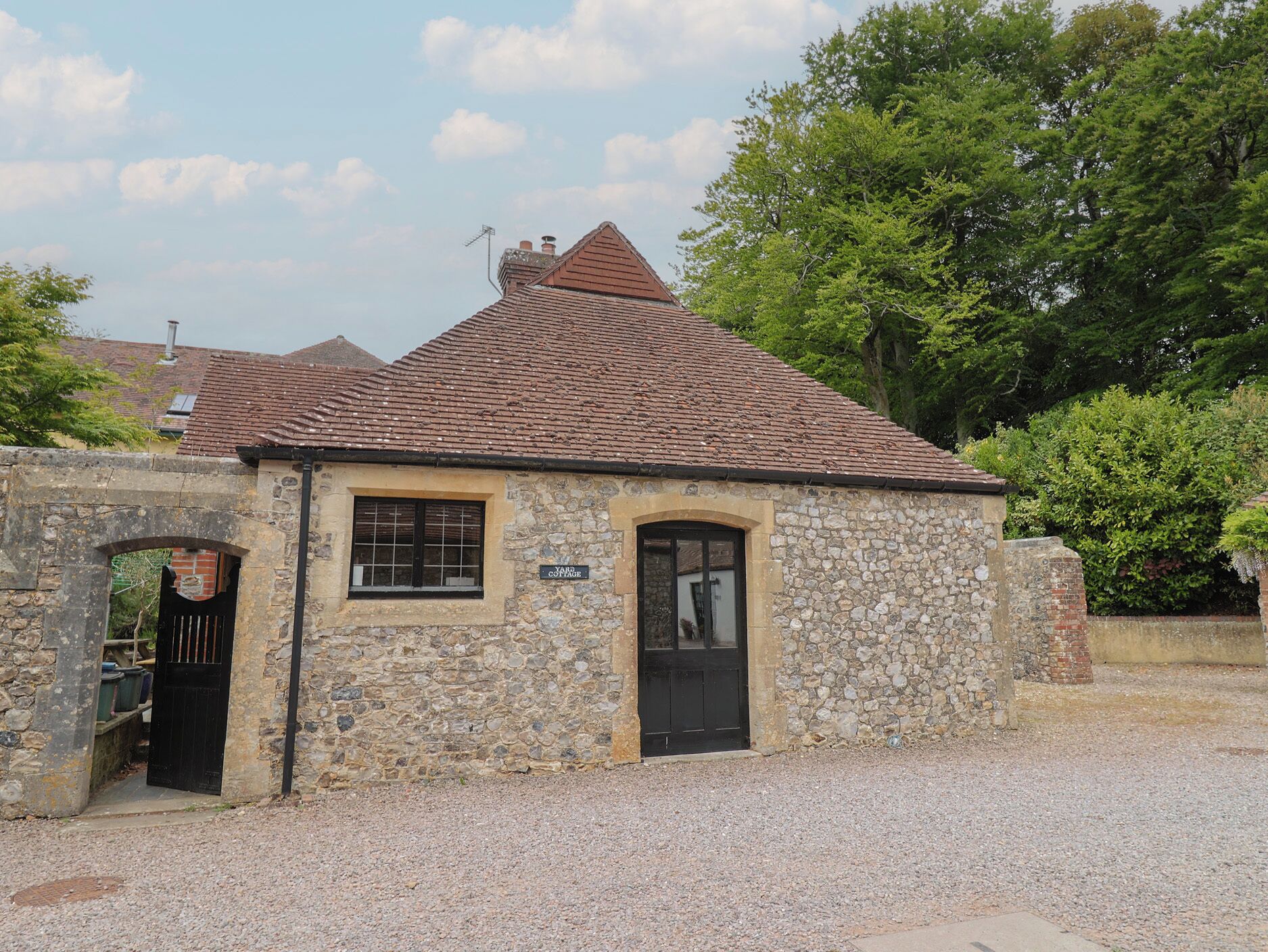 A stone building with a tiled roof, a black door, and a window.
