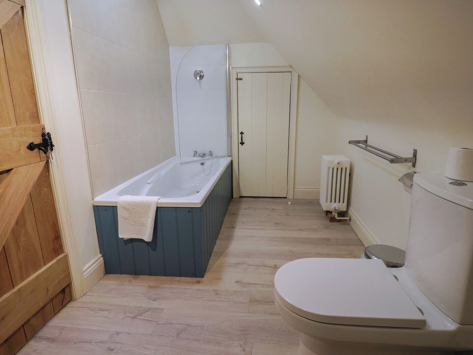 Un bagno con vasca, servizi igienici e una porta che dà su un'altra stanza.