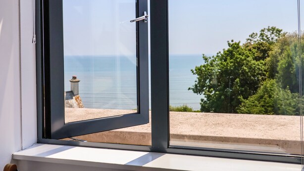 Ein Fenster mit Blick auf das Meer und einen Sandstrand.