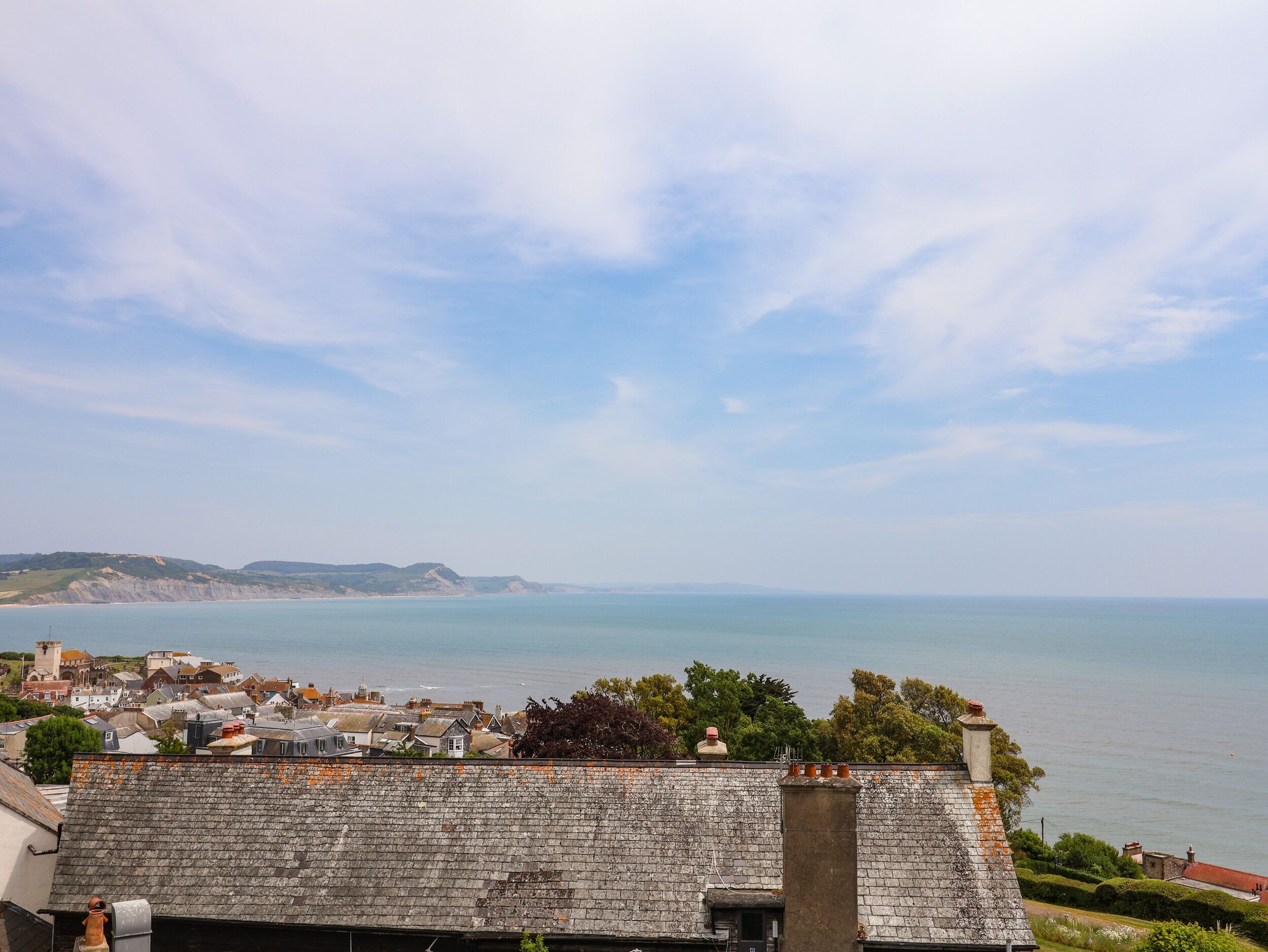 Un pueblo costero con edificios de piedra, vista al mar y cielo despejado.