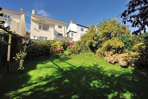 A residential area with two white houses, a well-maintained lawn, and dense shrubbery. - Greystones (Lyme Regis)
