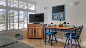 Ein Essbereich mit einem Holztisch, blauen Stühlen und einem Fernseher auf einem Schrank.